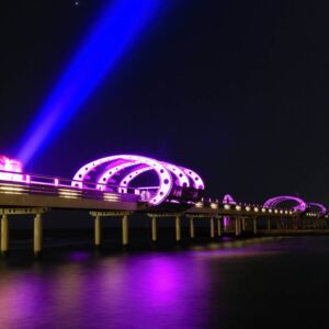 Die Kellenhusener Seebrücke, die lila illumiminert ist mit einem Laserlicht das gen Himmel strahlt