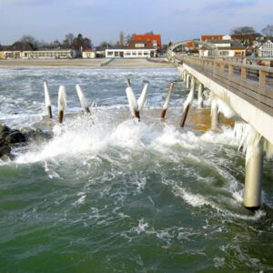 Die vereiste Kellenhusener Seebrücke im Winter, die Wellen schlagen an der Plattform hoch